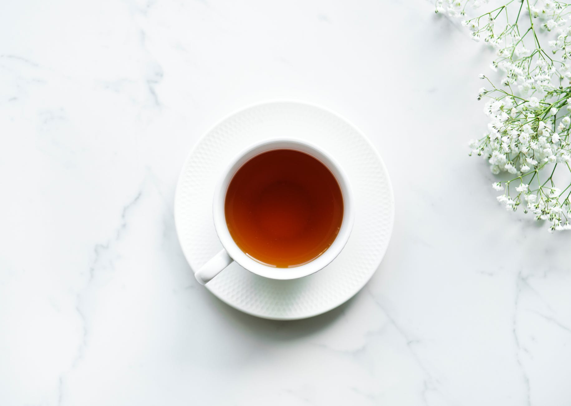 white ceramic teacup on saucer with brown liquid