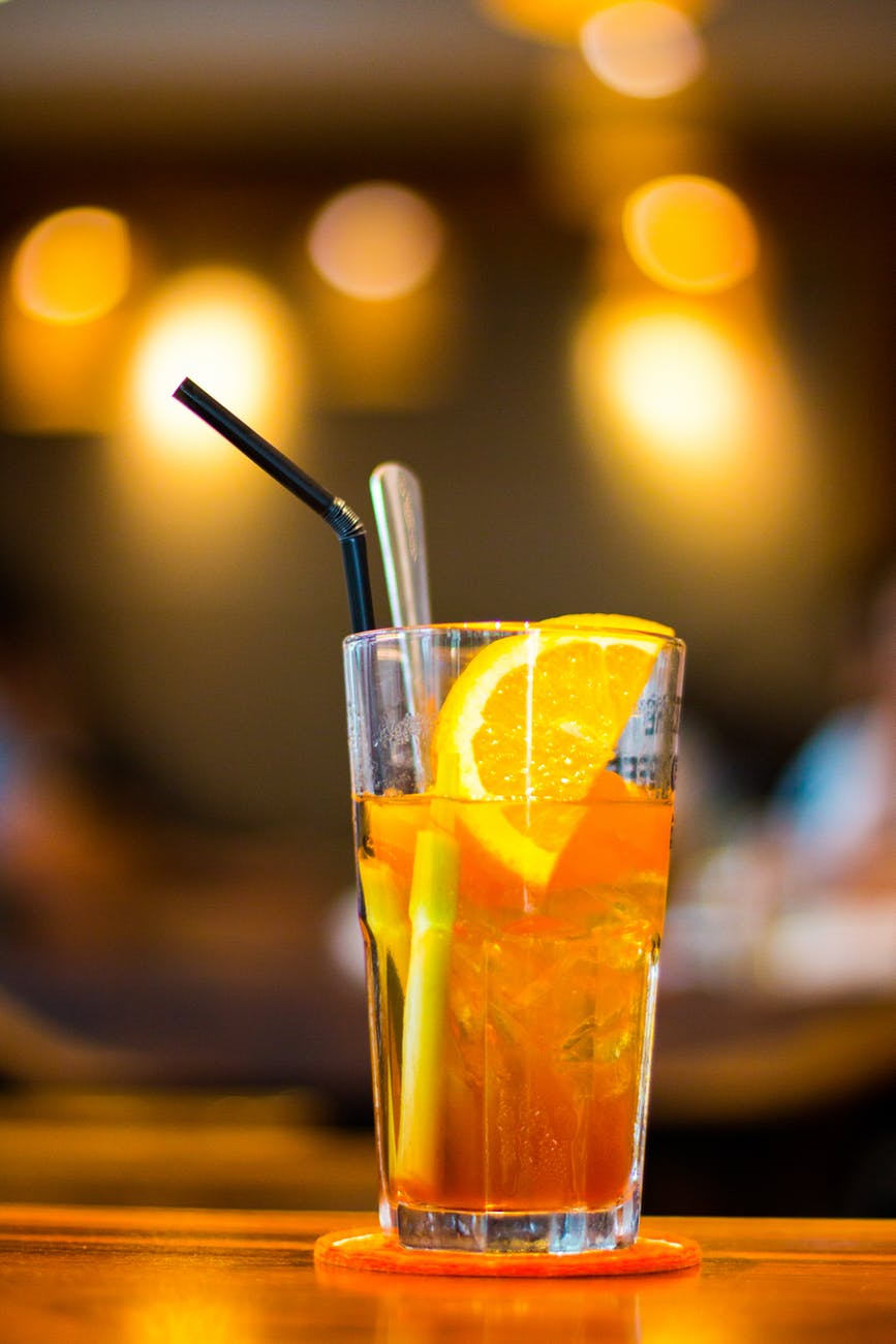 macro photography of clear drinking glass with lemon fruit and black straw