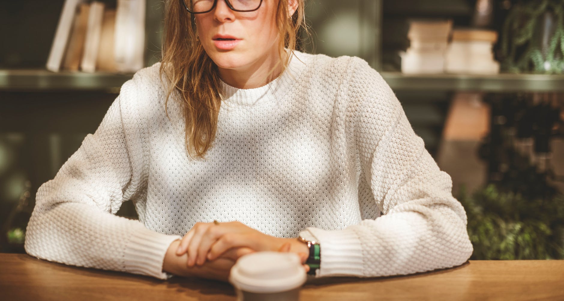 woman wearing white sweater sitting beside table